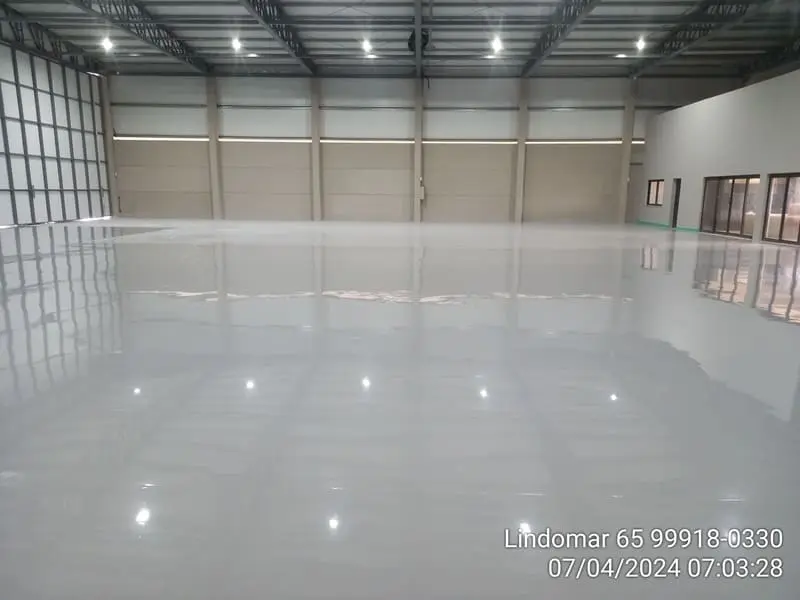 Piso epóxi autonivelante cinza aplicado em galpão industrial em Sinop MT com acabamento de alto brilho