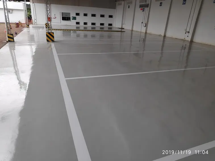 Piso industrial epóxi em área coberta com veículos pesados e acabamento brilhante em Barra do Garças MT